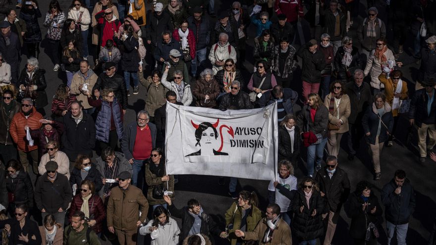 Manifestantes de la Comunidad de Madrid cargan una pancarta contra la presidenta de la región, Isabel Díaz Ayuso.