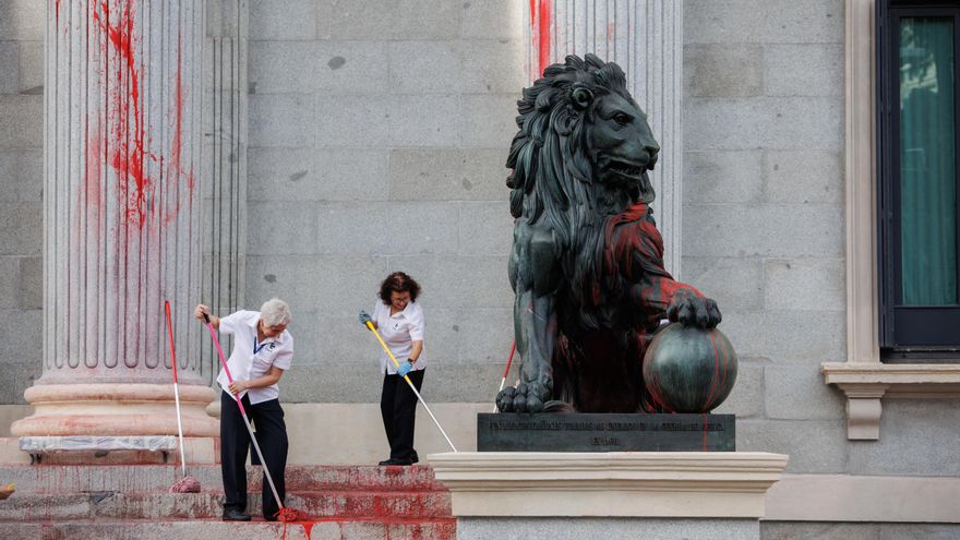 Dos operarias limpian el león del Congreso tras la protesta de marzo de 2023.