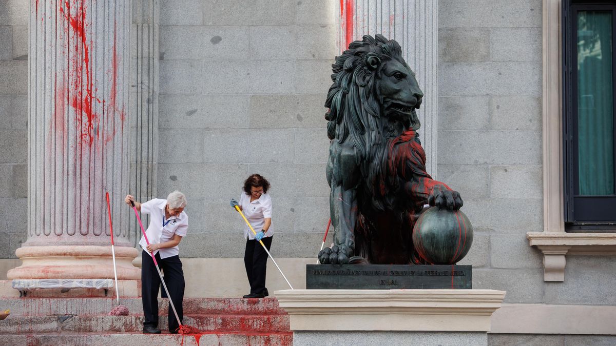 Dos operarias limpian el león del Congreso tras la protesta de marzo de 2023.