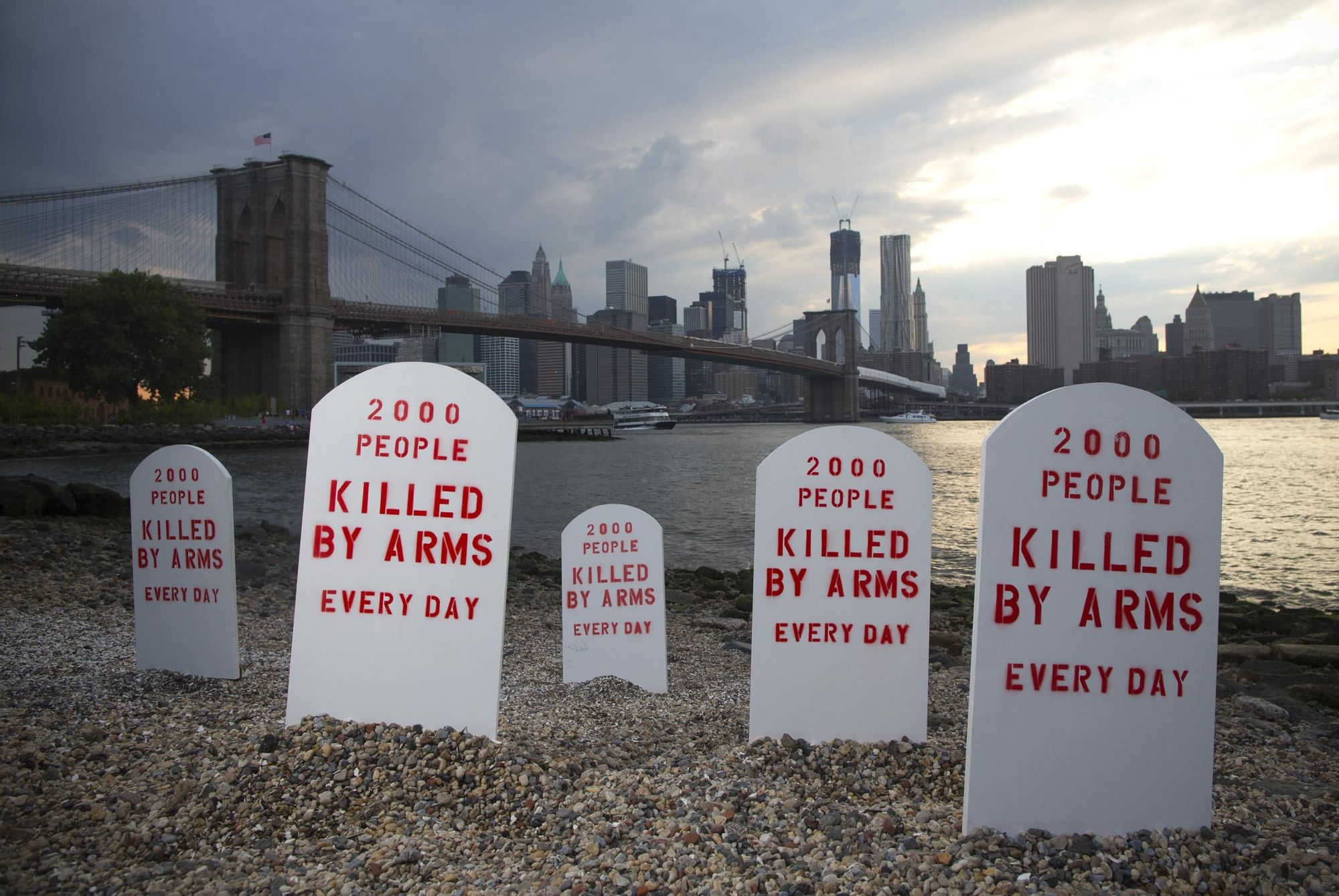 JULIO. Las medidas de control no parecen tener el mismo peso cuando lo que circulan no son personas sino armas. Estas lápidas colocadas a la orilla del East River, en Brooklyn, Nueva York, simbolizan el número de personas asesinadas por la falta de un comercio regulado: 2.000 personas son asesinadas con armas cada día. #TratadoArmas // © Andrew Kelly