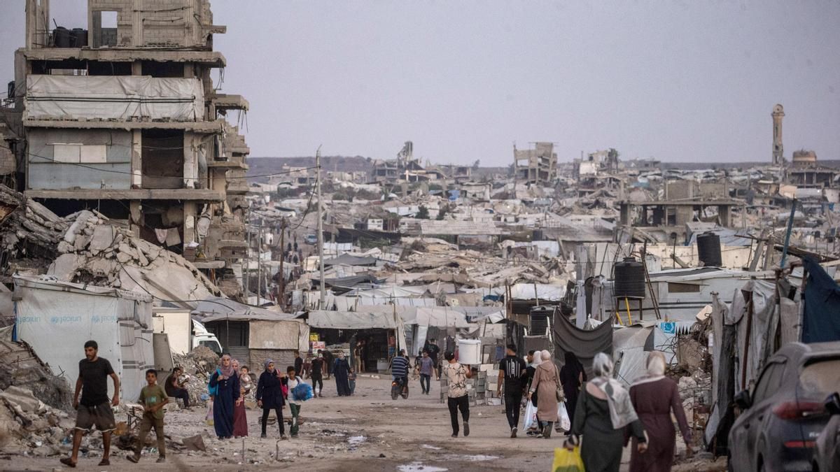 Palestinos desplazados internamente caminan entre las ruinas de edificios residenciales destruidos en el barrio de Al-Sheikh Radwan, al este de la ciudad de Gaza.