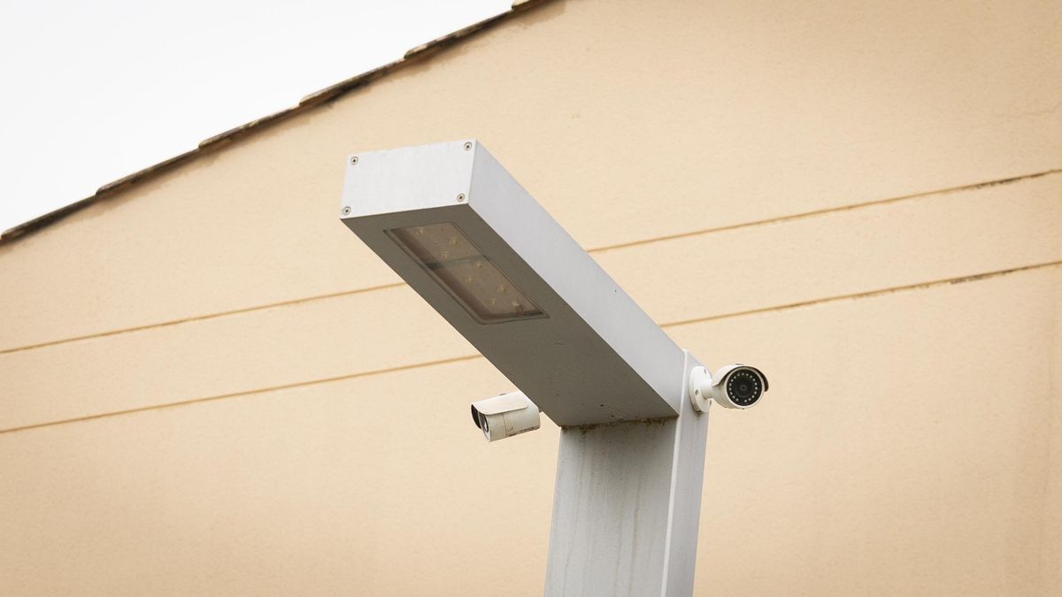 Farola del parque infantil con dos cámaras orientadas hacia la zona de juegos, que registran de forma constante la actividad de niños y familias.