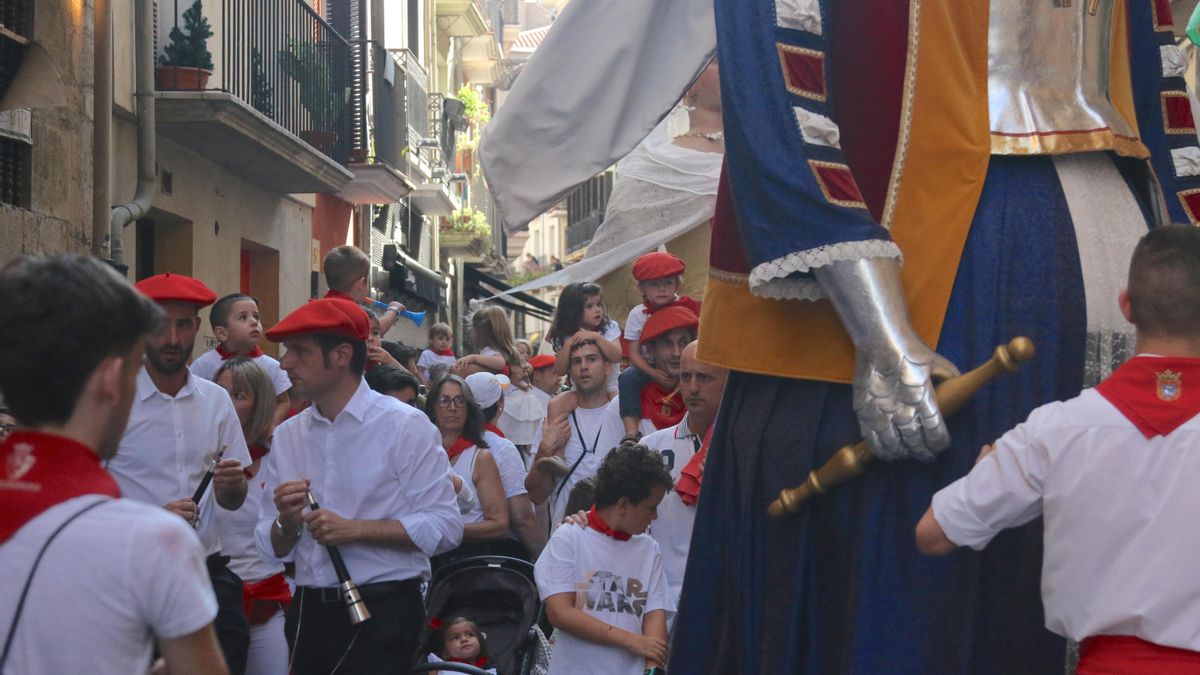 Comparsa de gigantes y cabezudos de Pamplona recorriendo las calles durante San Fermín, acompañados de familias y niños que disfrutan de la tradición