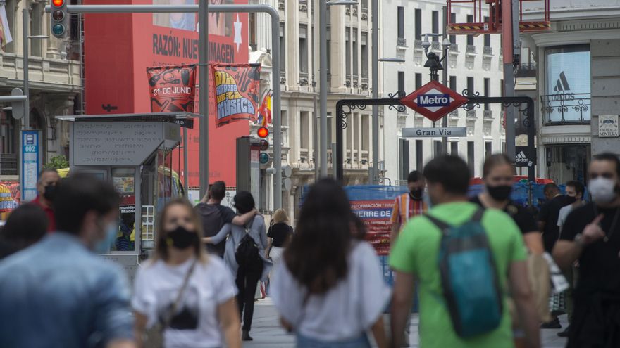 Varias personas caminan por la Gran Vía con mascarilla