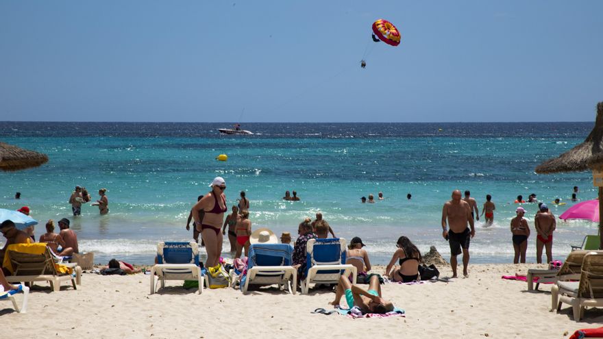 Turistas y locales toman el sol y practican deportes acuáticos en Sa Coma.