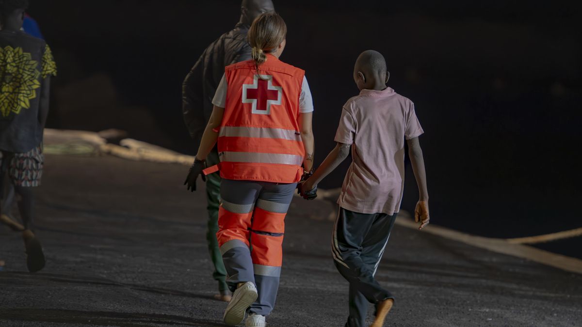 Un trabajador de la Cruz Roja atiende a uno de los migrantes que ha llegado al Puerto de La Restinga