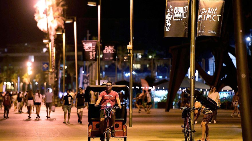 Un conductor de bici-taxi circula por la noche en Barcelona, durante el mes de julio de 2022