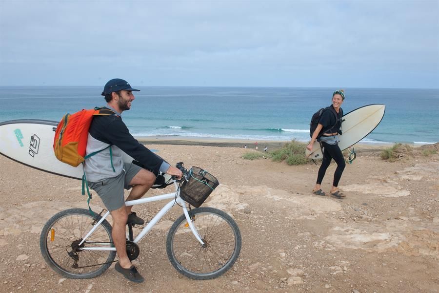 Dos personas regresan a casa después de haber practicado surf en la playa del Cotillo, Fuerteventura (Efe / Carlos De Saá)
