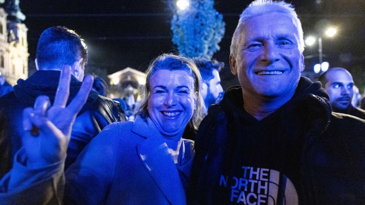 Una pareja hace el símbolo de la victoria en la plaza donde Péter Magyar anunció su victoria.