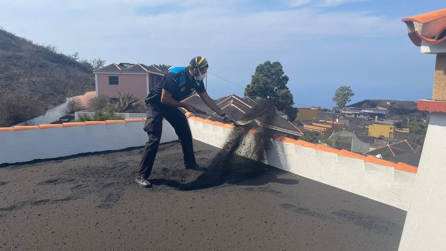 Un voluntaria de la Autorizada Portuaria retira ceniza del volcán en una vivienda.