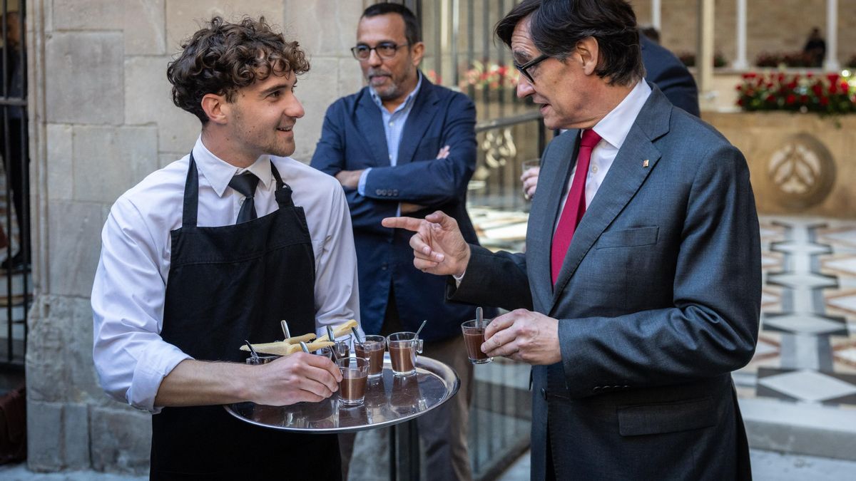 El president Illa, hablando con uno de los camareros de la 'chocolatada' celebrada en el Pati dels Tarongers