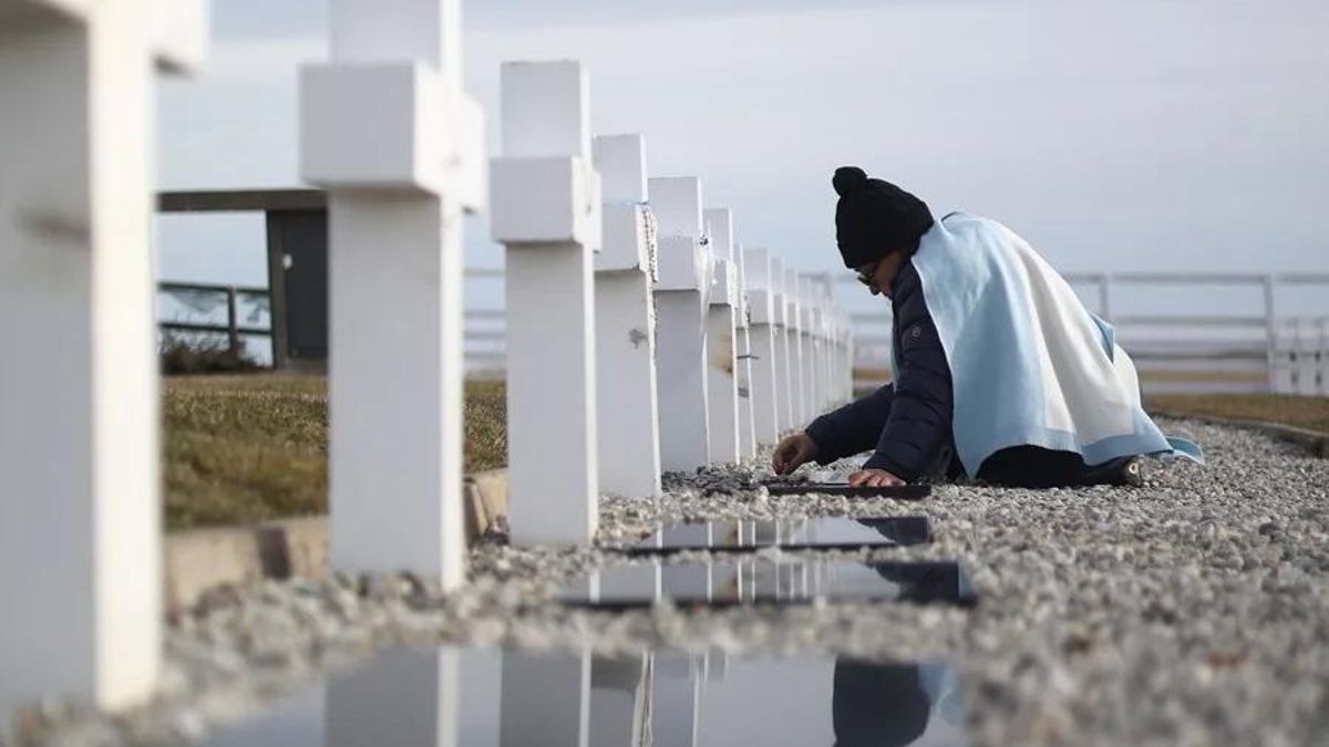 Una mujer con la bandera de Argentina visita una tumba, en el Cementerio Militar Argentino de Darwin, en las Islas Malvinas.