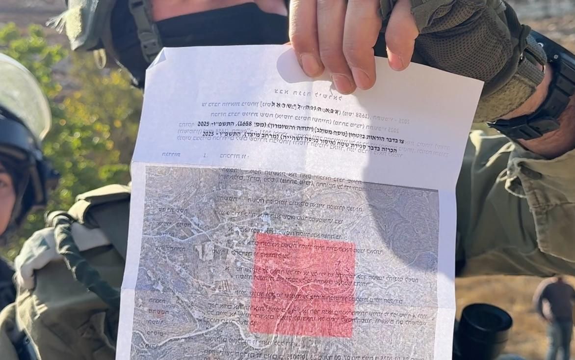 Un soldado israelí muestra la orden del ejército que delimita los olivares de Sair como zona militar.