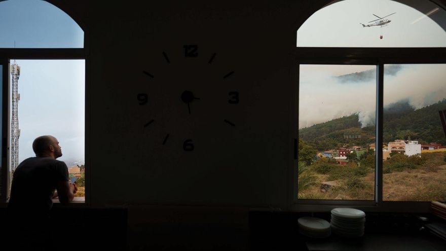 Un hombre observa desde una ventana de un restaurante de Aguamansa, en el municipio de La Orotava, los trabajos de los helicópteros que trabajan en la extinción del incendio forestal que afecta a varios municipios de la isla de Tenerife. EFE/Ramón de la Rocha