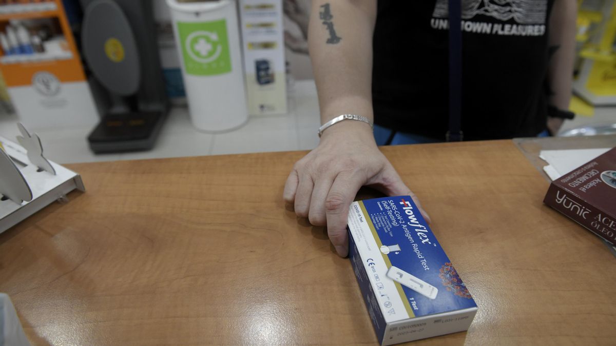 Archivo - Un cliente enseña un test de antígenos de detección del COVID-19 en una farmacia, foto de archivo