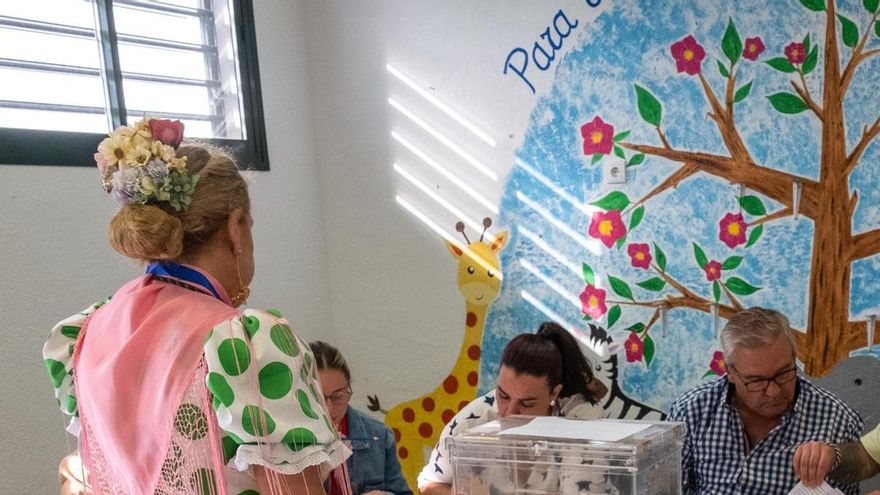 Una mujer vestida de rociera ejerce su derecho a voto en un colegio de Huelva