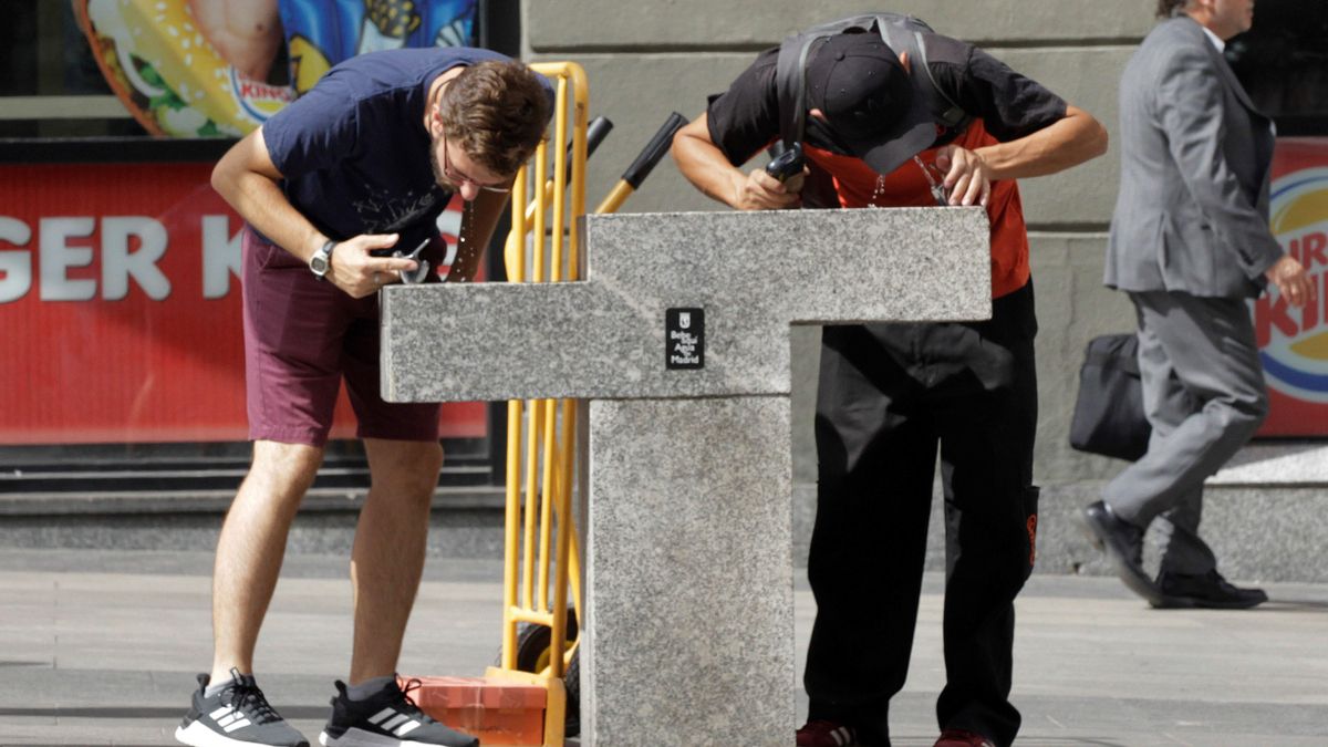 Dos personas beben agua en una fuente