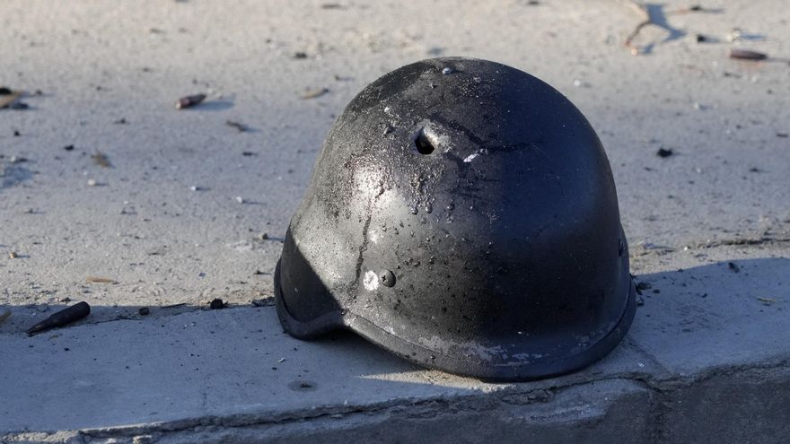 El casco de un soldado con un agujero de bala cerca de los restos de los camiones militares en llamas, en una calle de Kiev.