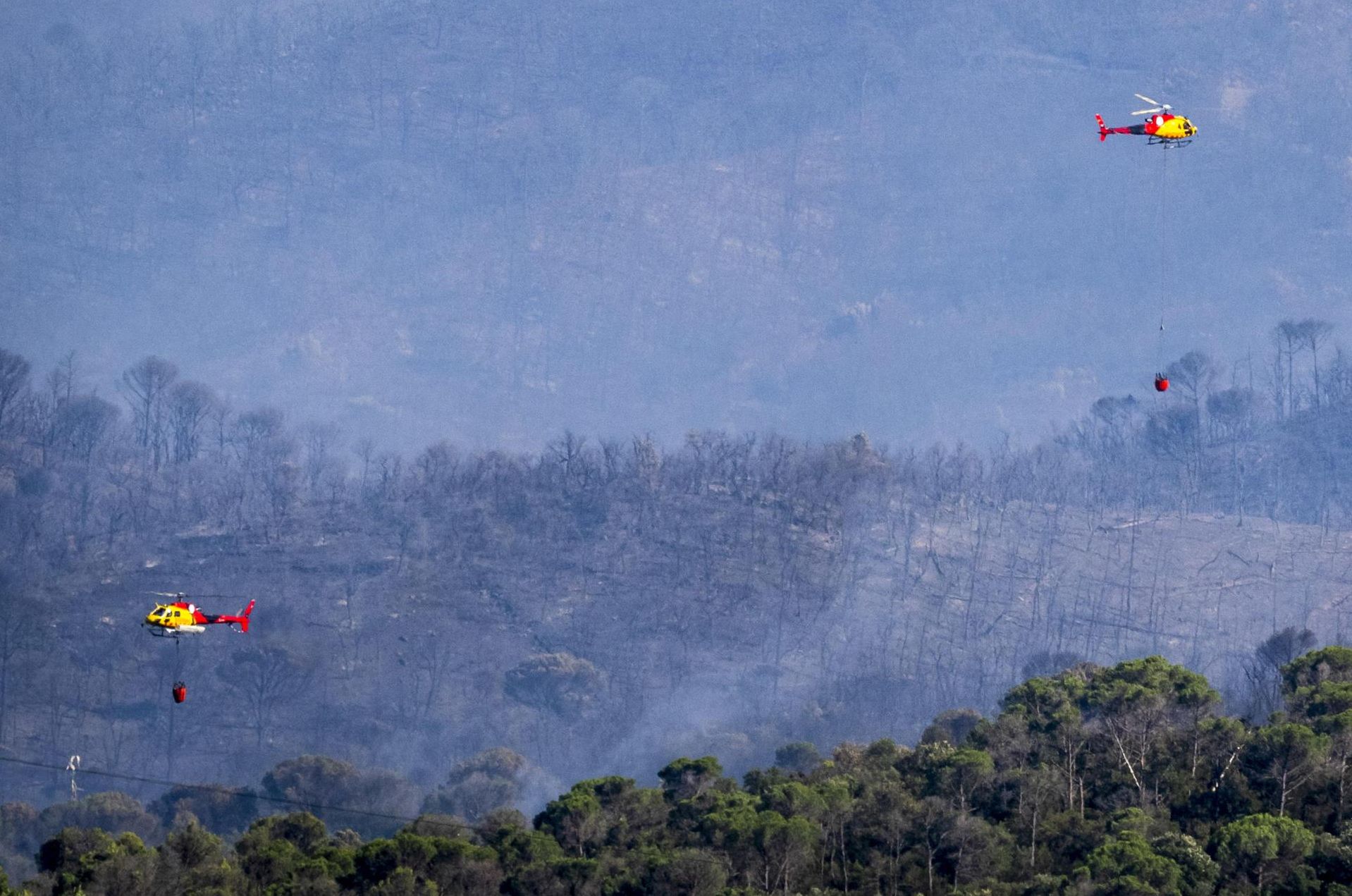 Helicópteros tratan de apagar las llamas en Les Gavarres, este viernes