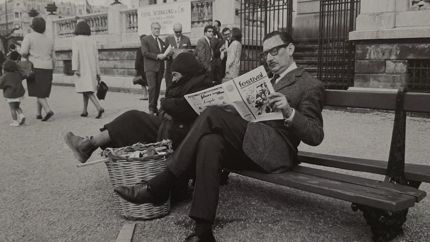 Un señor lee el periódico del Festival junto a un vagabundo, año 1965.