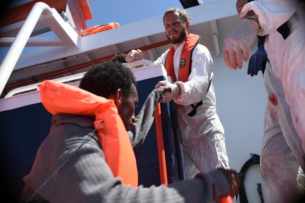 Un miembro del equipo de MSF ayuda a subir al MY Phoenix a uno los refugiados que viajaban en una embarcación de madera de 12 metros de eslora donde trataba de llegar a Europa junto a 368 personas. Fotografía: Ikram N'gadi