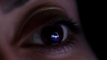 A photo illustration shows the Disney Plus streaming service logo reflected in an eye.