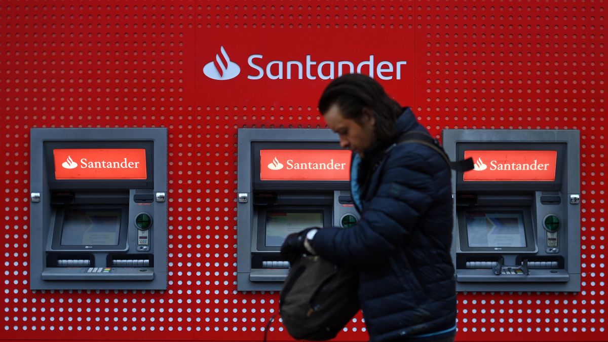 Una persona camina por delante de cajeros del banco Santander en una foto de archivo