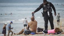 Un oficial de policía recuerda que no está permitido tomar el sol en Palm Beach, Florida, este 18 de mayo