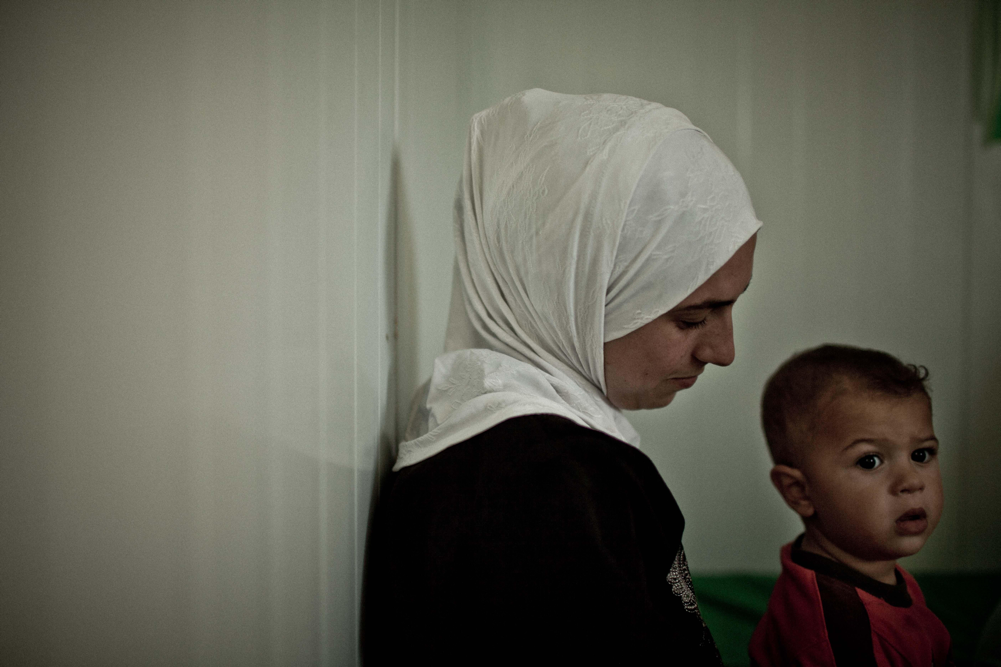 Una joven procedente de la ciudad siria de Der’a coge a su hijo en brazos en el contenedor donde viven en el campo de Za’atari./ Fotografía: Pablo Tosco/ Intermón Oxfam.