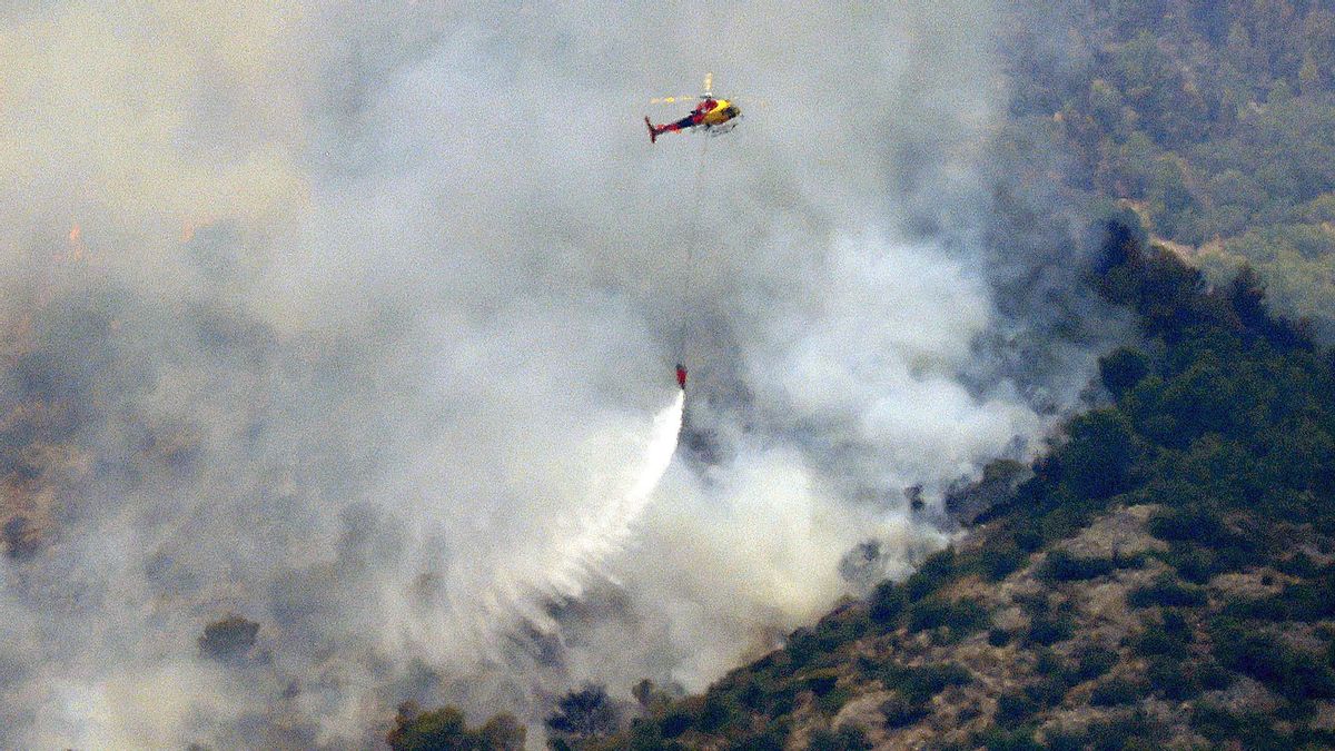 Un helicóptero trabaja en la tareas de extinción del incendio forestal de alta intensidad que se inició ayer en Paüls (Tarragona) y que afecta ya a un total de 3.137 hectáreas, en su mayoría forestales y de ellas más de mil dentro del Parque Natural de Els Ports.