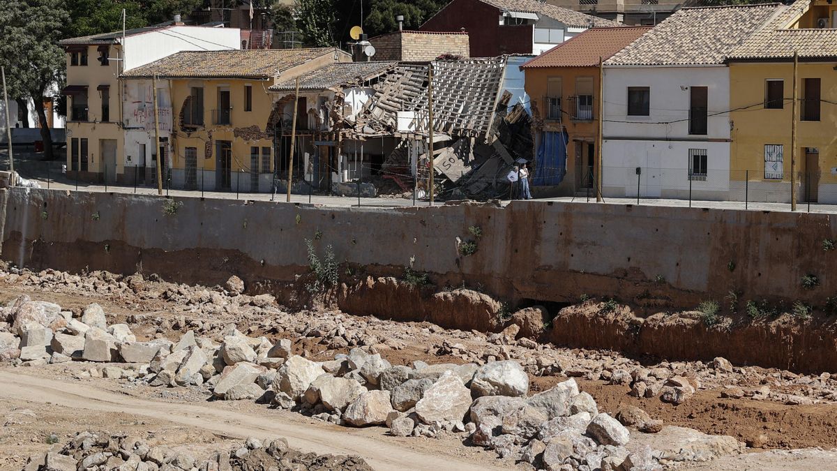Dos personas pasean junto al barranco del Poyo a su paso por Picanya y donde los daños causado por la inundación son claramente visibles.