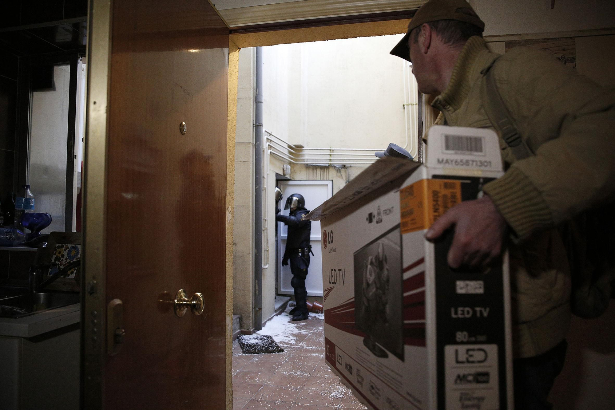 Umberto sacando parte de sus pertenencias mientras la policía permanece en el patio de  entrada de la vivienda. Sólo pudo llevarse una bolsa de deporte y la caja con la televisión que se ve en la fotografía.