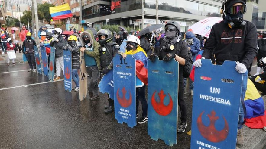 Integrantes de la llamada "primera linea" de defensa del Paro Nacional sostienen sus escudos caseros mientras participan en una nueva jornada de protestas este martes, en Bogotá (Colombia).