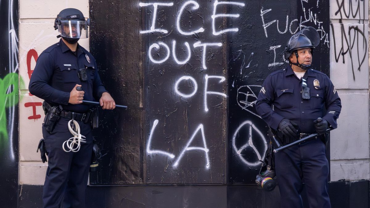 La policía hace guardia junto a un muro con el lema "ICE fuera de Los Ángeles" durante las protestas contra las redadas que tuvieron lugar en junio en Los Ángeles.