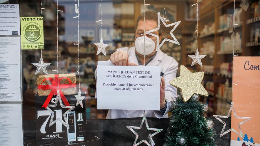 El farmacéutico cuelga el cartel de que los test de antígenos de la Comunidad de Madrid están agotados en la farmacia de la Calle Tucán, en el distrito de Carabanchel, a 21 de diciembre de 2021, en Madrid (España).