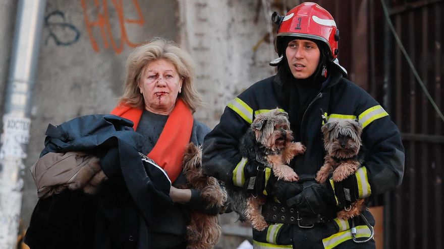 Un rescatista ucraniano ayuda este lunes a una mujer herida y a sus perros tras un bombardeo en el centro de Kiev.