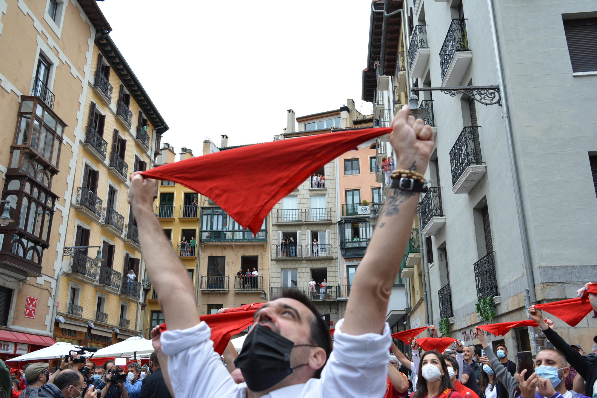 Varias personas levantan los pañuelos rojos a las 12 del mediodía en la plaza del Ayuntamiento de Pamplona