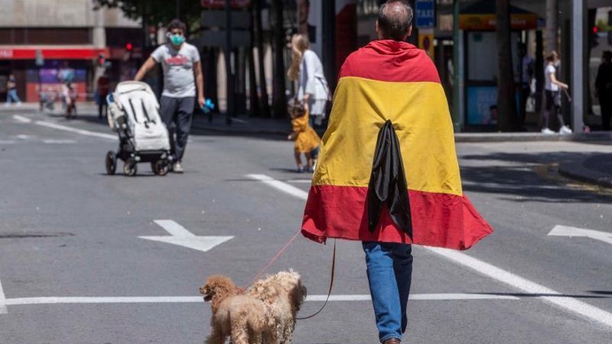 Un hombre con una bandera de España con crespón negro pasea con sus perros por la gran vía de Murcia.