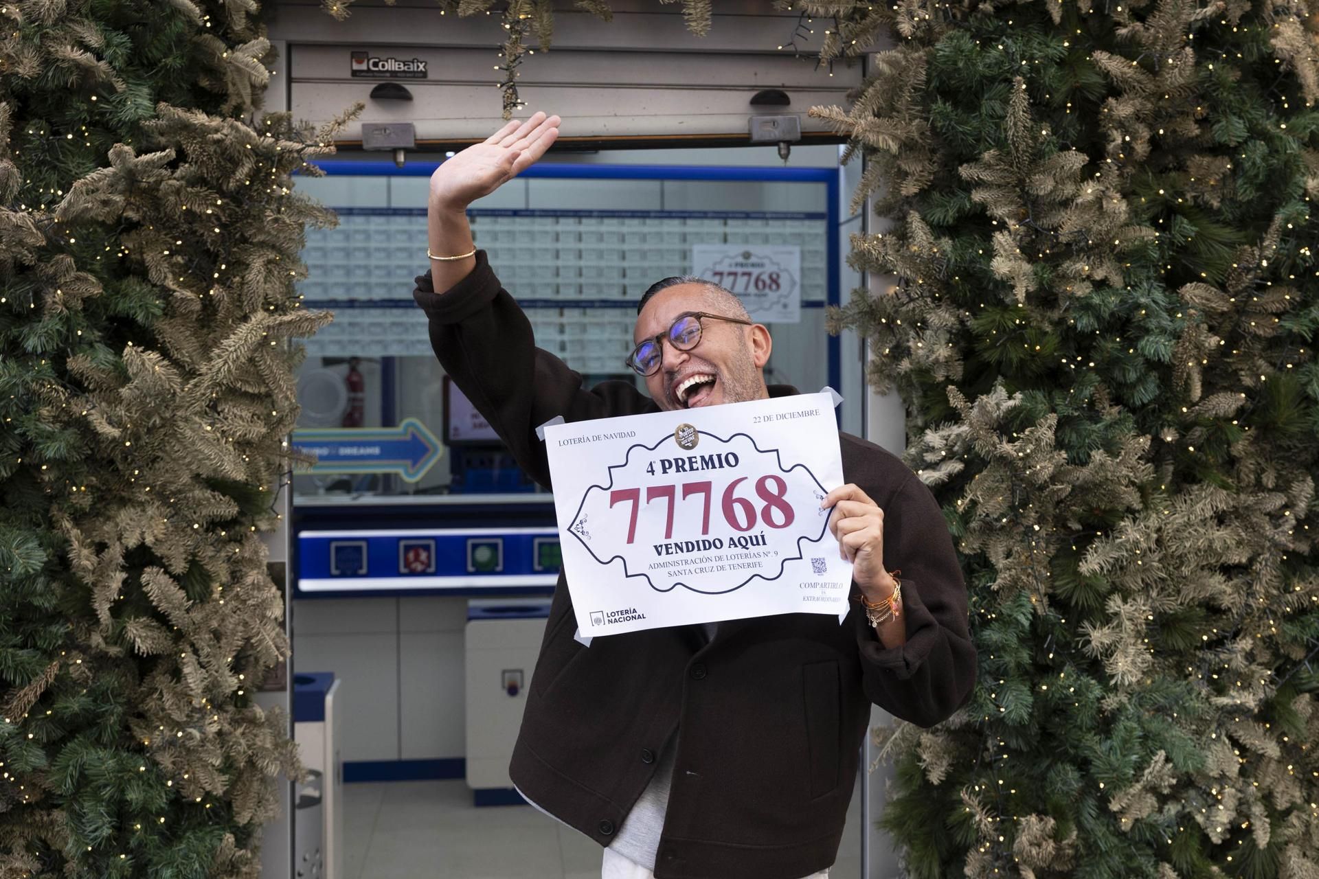 El dueño de la administración número 9 en Santa Cruz de Tenerife, Hari Satyani, posa con el número 77768, agraciado con uno de los cuartos premios del sorteo extraordinario de Navidad de la Lotería Nacional. EFE/ Miguel Barreto