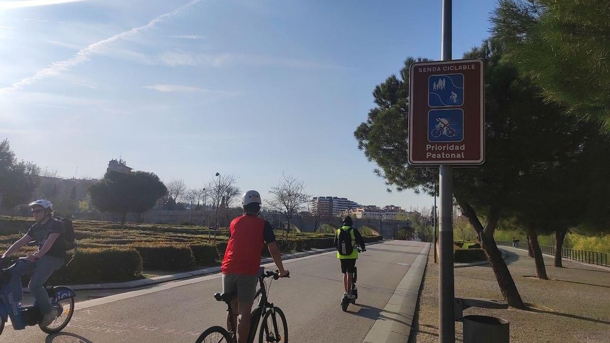 Dos ciclistas y una persona en patinete eléctrico en Madrid Río.