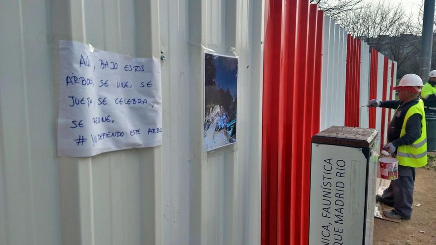Obrero tapando las pintadas contra la tala en las vallas de Madrid Río.