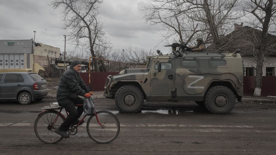 Un lugareño pasaba con su bicicleta frente a un vehículo militar ruso durante la distribución de alimentos organizada por el ejército ruso y las milicias de la autoproclamada República de Lugansk en la aldea de Trokhizbenka, el pasado mes de marzo. EFE/EPA/SERGEI ILNITSKY