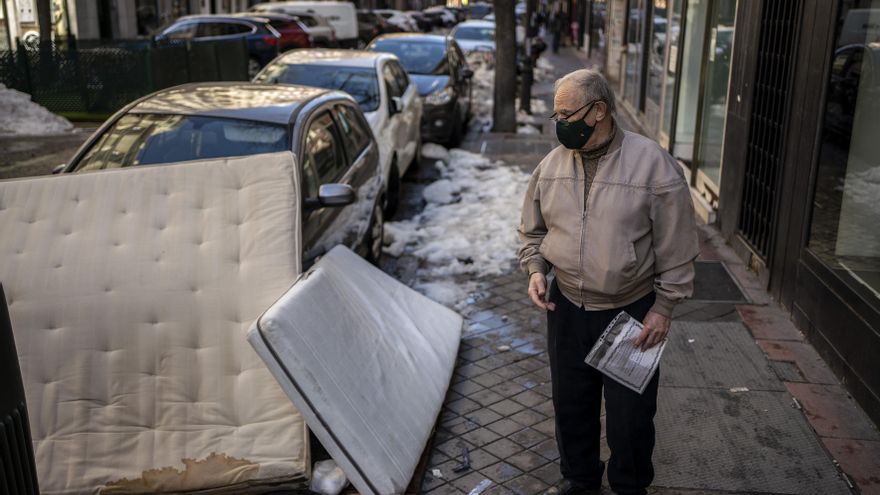 Rafael mira unos colchones tirados junto a unos contenedores de reciclaje en la calle General Pardina, Madrid.