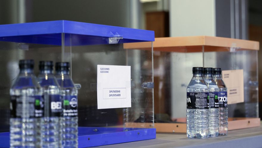 Detalle de las urnas y las botellas de agua dispuestas para los miembros de las mesas electorales durante el montaje de un colegio electoral para las Elecciones Generales del 23J en Barcelona. EFE/Quique García