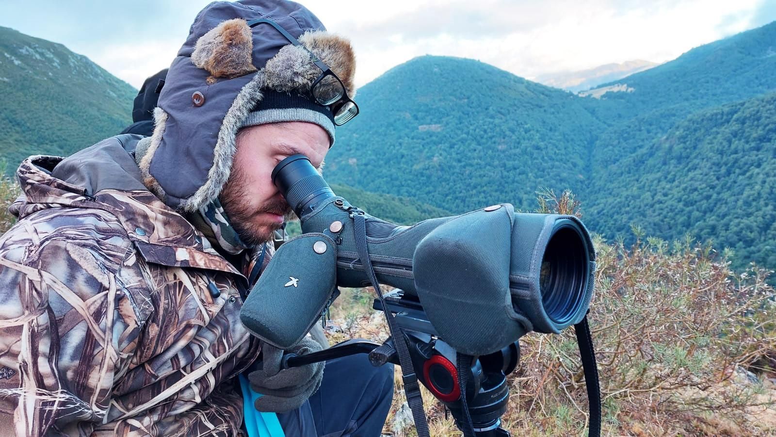 El biólogo de la ULE, Héctor Ruiz Villar, realizando trabajo de campo observando con un catalejo.