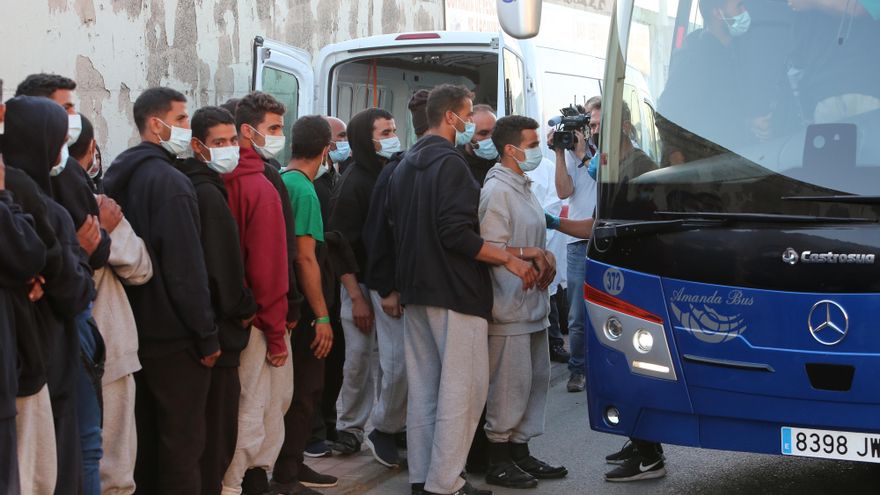 Varias personas migrantes suben a una guagua para ser trasladados a Las Palmas de Gran Canaria después de que la Policía Nacional sacara a un grupo de entorno a 200 del muelle de Arguineguín.