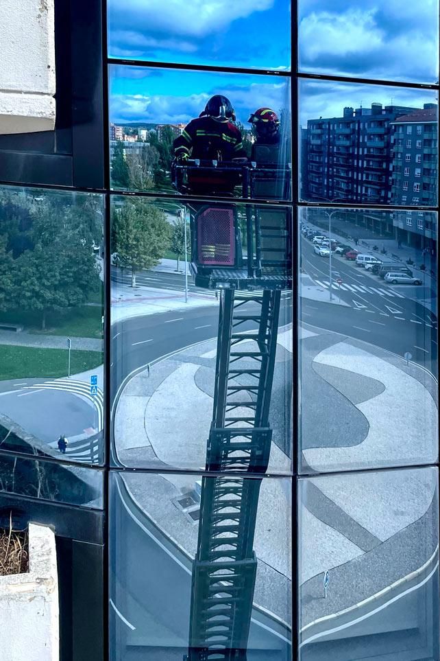 Los bomberos de León trabajando en la fachada de cristal debilitada.