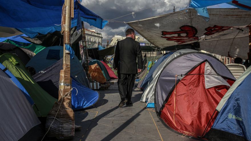 04/06/2011. Un hombre trajeado cruzando uno de los pasillos de la acampada que se levantó en Sol.