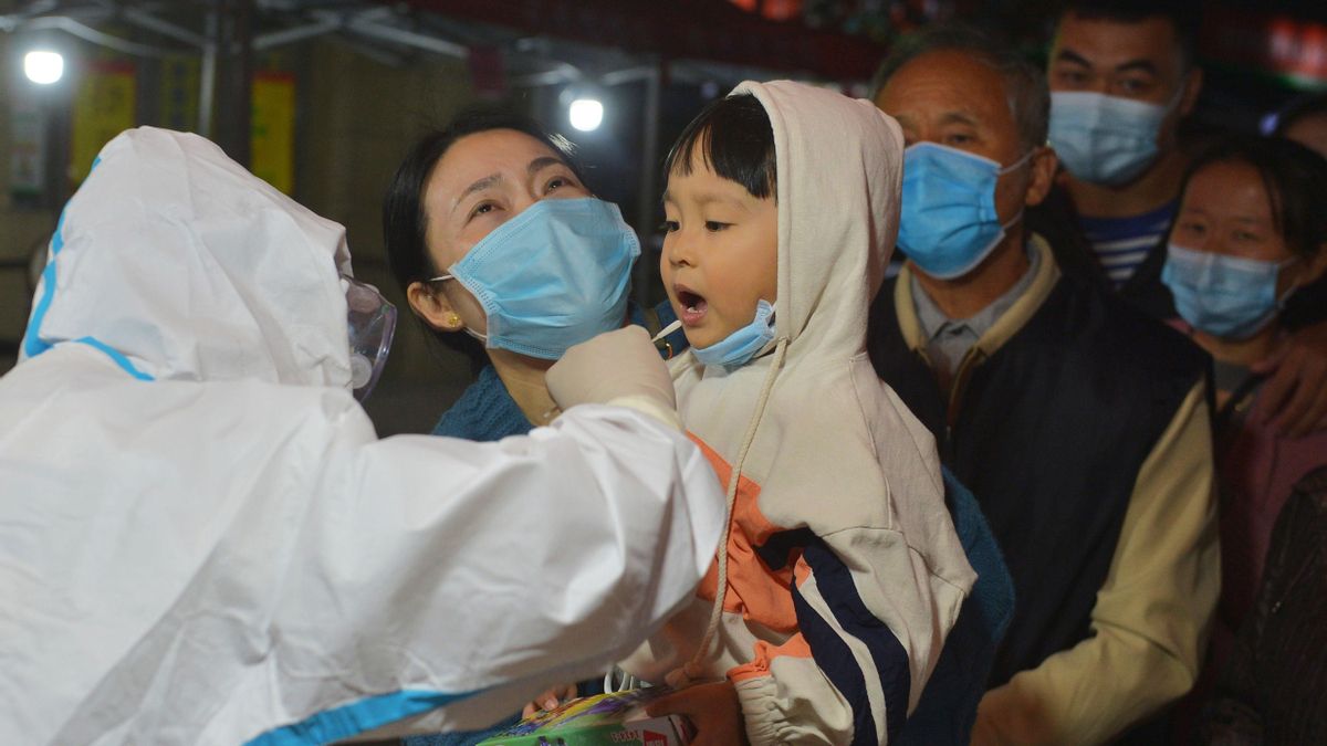 Un trabajador médico toma una muestra de hisopo de un niño residente para la nueva prueba de coronavirus en un bloque residencial en la ciudad de Qingdao, provincia de Shandong, China. EFE/EPA/WANG HAIBIN