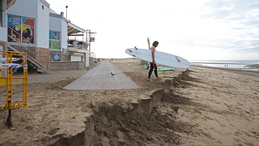 Un surfista en el tramo del paseo de Maspalomas afectado por la subida de la marea.